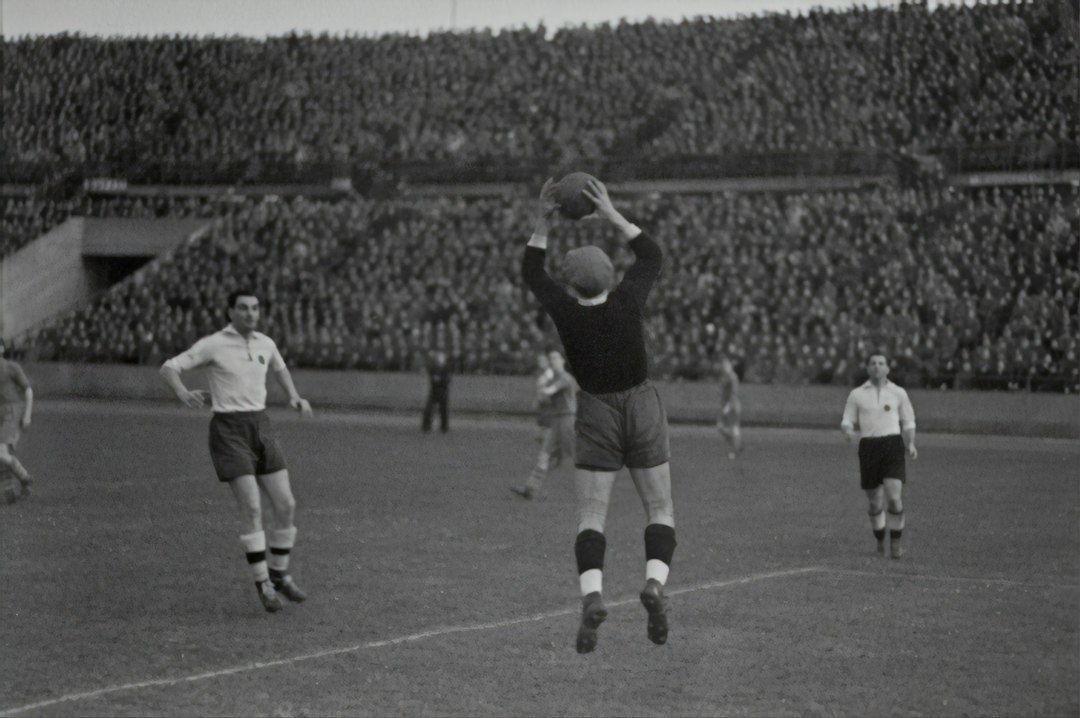 Historische Fußballszene mit springendem Spieler und dicht besetzten Tribünen
